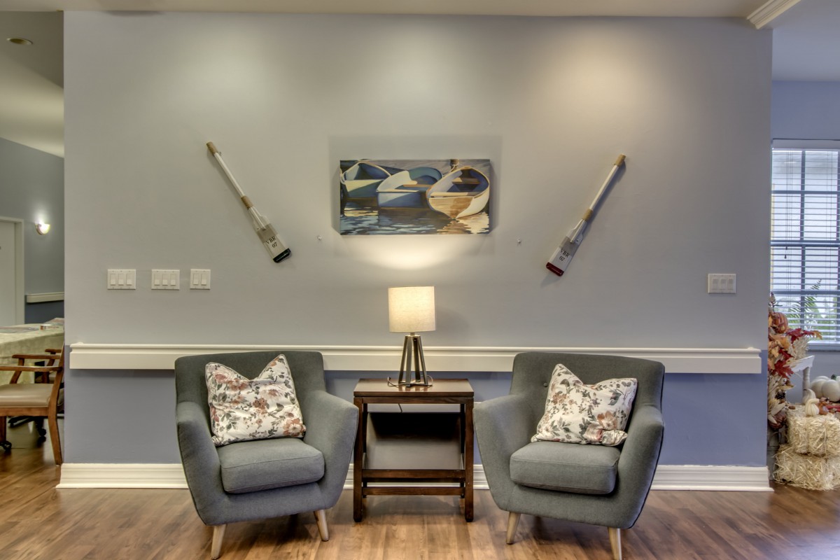 A cozy seating area featuring two armchairs, a lamp, and abstract wall art.