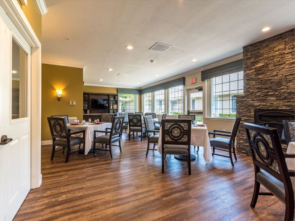 A cozy dining area with wooden flooring and large windows providing natural light.