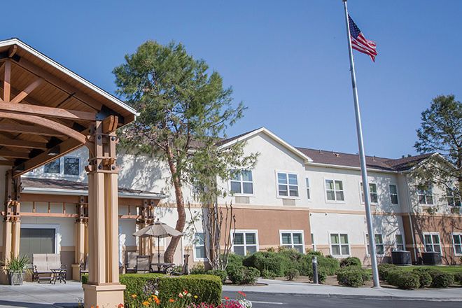 A residential building with a flagpole and trees in an outdoor setting.