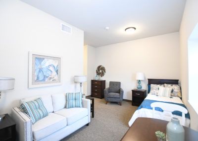 A cozy bedroom featuring a sofa, bed, armchair, and decorative elements.