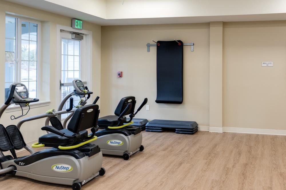 A gym room featuring two stationary bikes and wall-mounted exercise equipment.