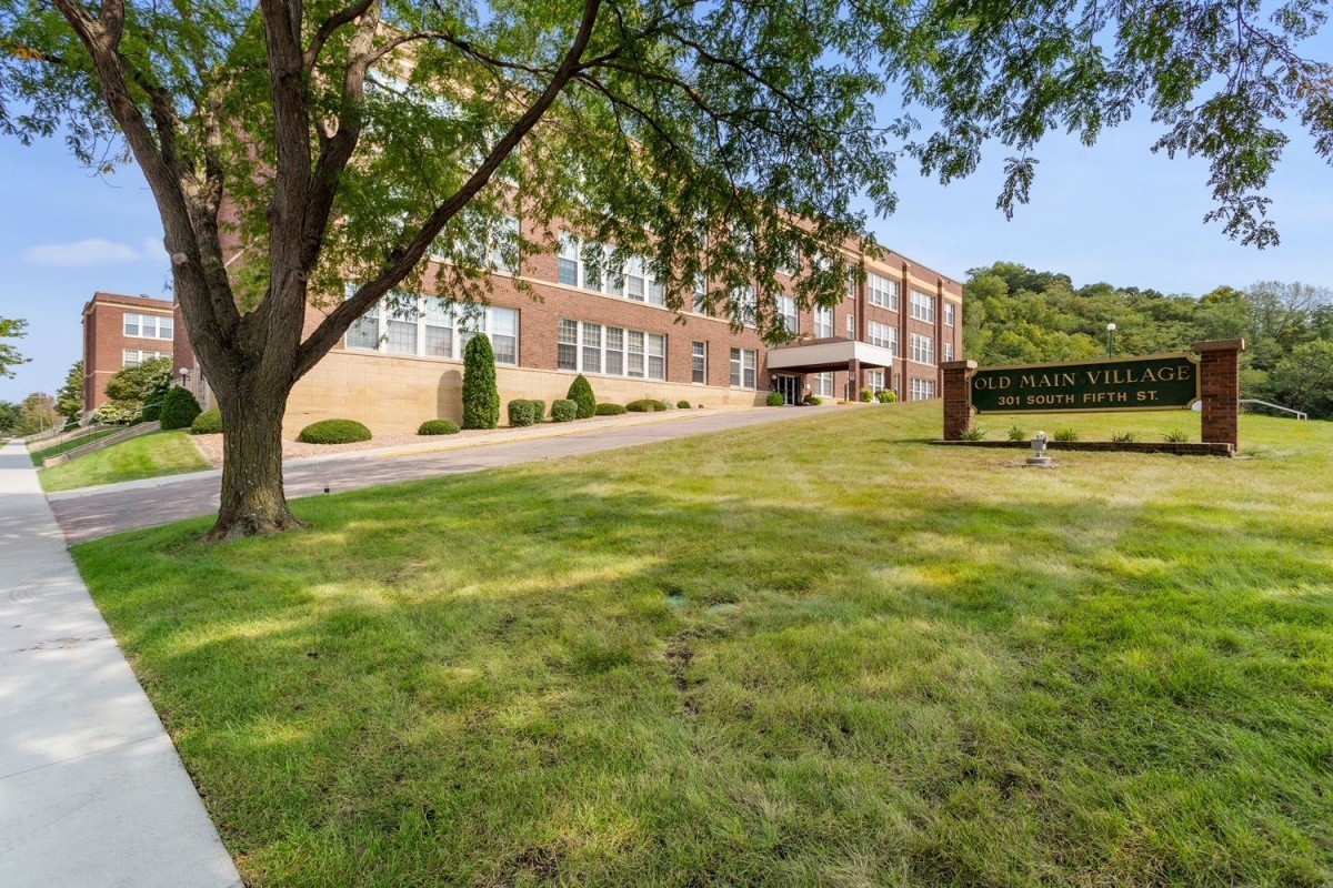 A sunny view of a school building with a lawn and trees.
