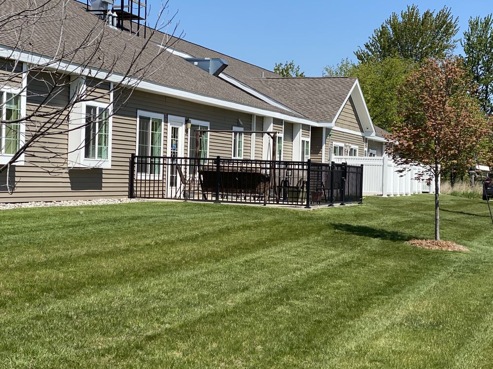 A backyard view of a house with a well-maintained lawn and patio area.