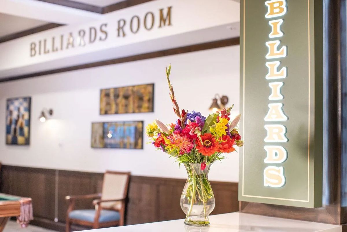 A colorful bouquet of flowers in a vase decorates the entrance to a billiards room.