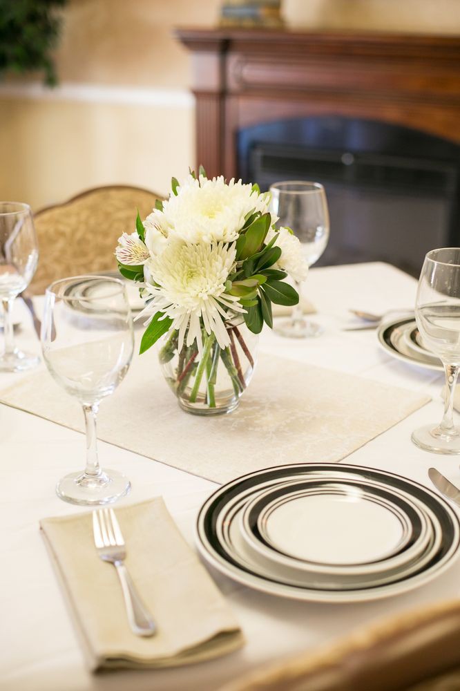An elegantly set dining table with a floral centerpiece and sophisticated dinnerware.