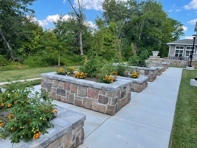 A beautifully landscaped garden with stone planters and a walkway surrounded by greenery.