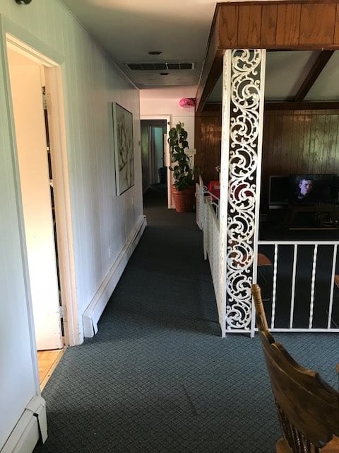 A hallway in an office space with a carpeted floor, decorative paneling, and a railing.