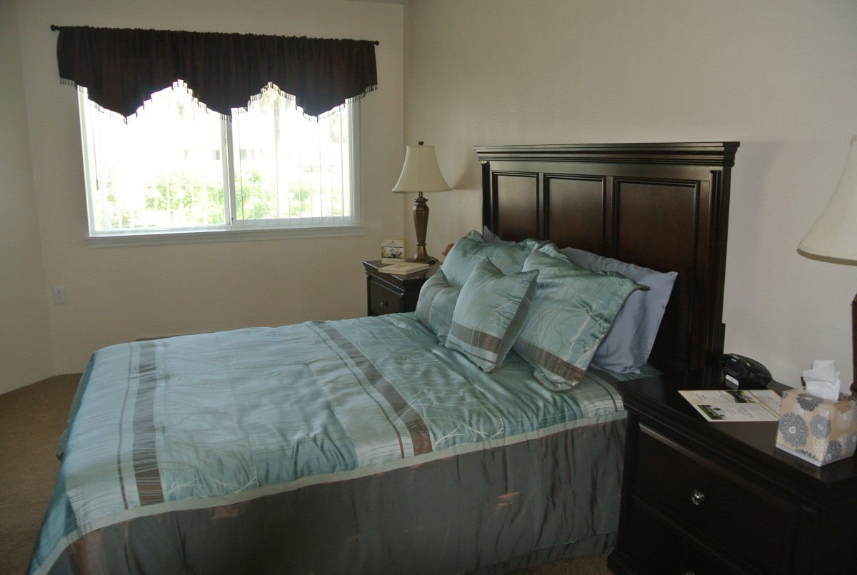A neatly arranged bedroom with a bed, lamp, and window.
