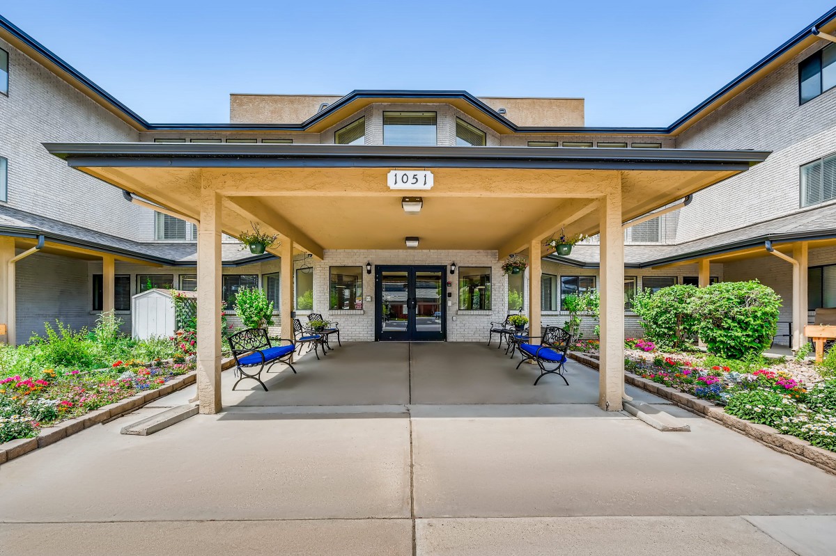 The entrance of a modern building with benches and landscaped surroundings.