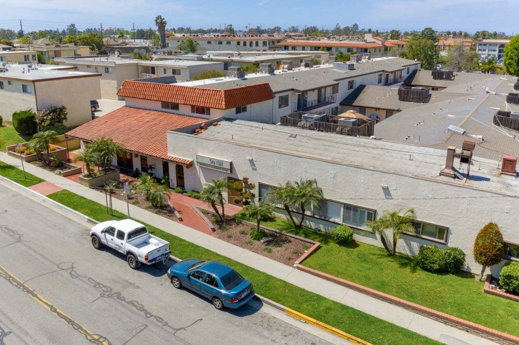 Aerial view of a residential area with parked cars and palm trees.