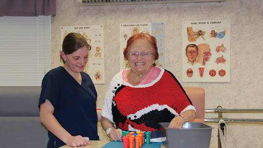 A joyful moment shared between a therapist and an elderly woman during a therapy session.