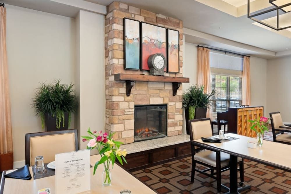 A cozy dining area featuring a brick fireplace, elegant decor, and comfortable seating.