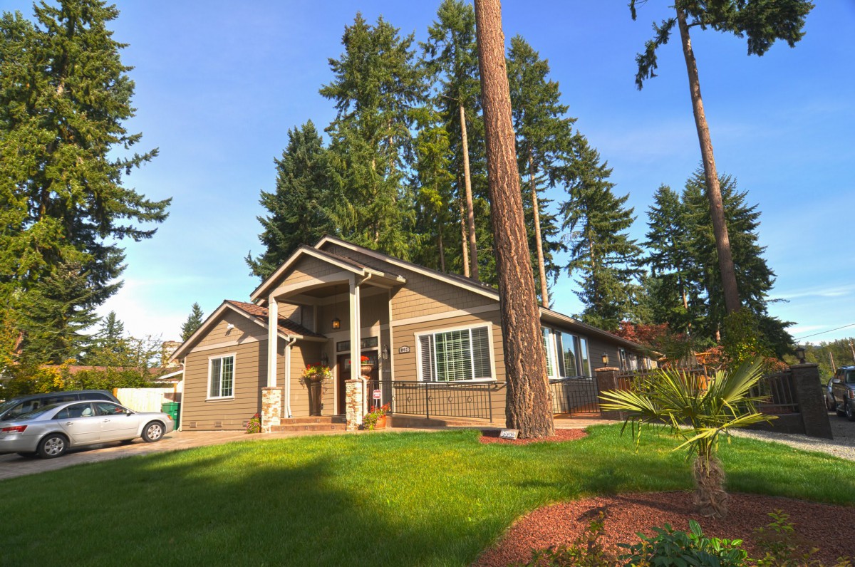 A charming house surrounded by tall trees on a sunny day.