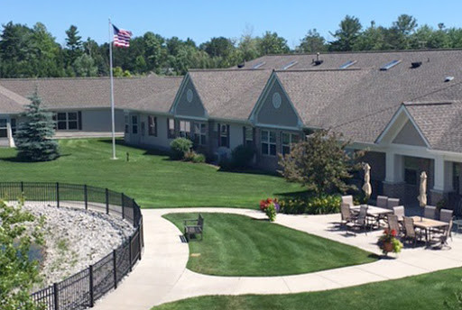 A sunny day at a well-maintained residential facility with landscaped gardens and a flag flying.