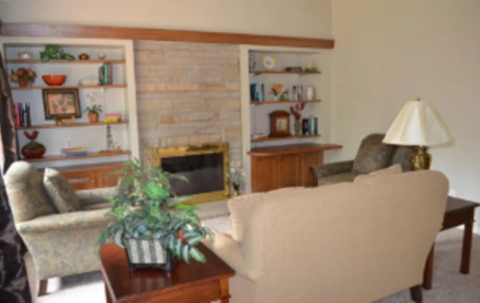 A cozy living room featuring a fireplace, surrounded by built-in shelves and comfortable furniture.