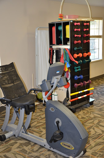 A well-equipped fitness area featuring a recumbent bike and various weight training equipment.