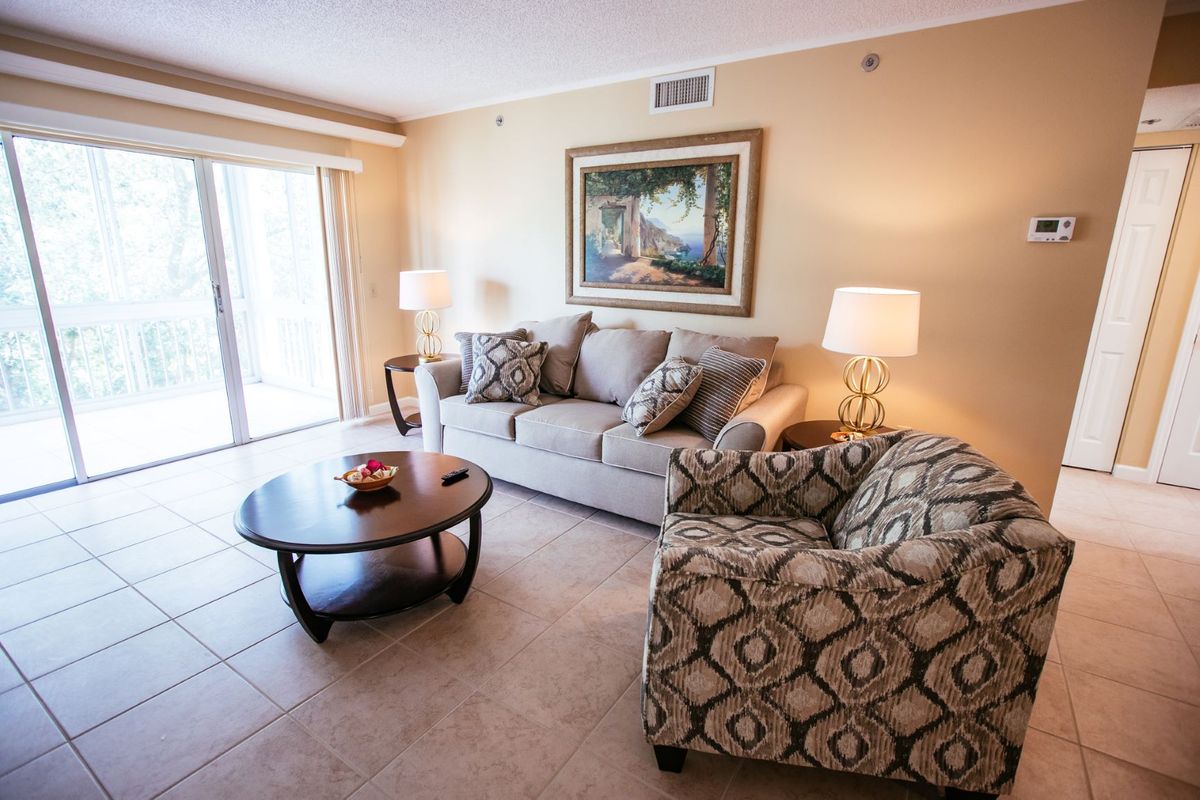 A cozy living room with a sofa, armchair, and coffee table set against a neutral color palette.