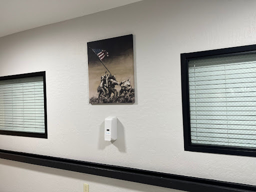 A framed black and white photograph depicting a historic military moment, displayed on a wall with windows.
