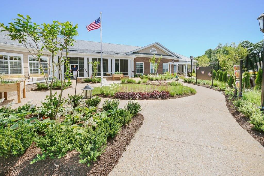 A beautifully landscaped pathway leading to a building with an American flag flying overhead.