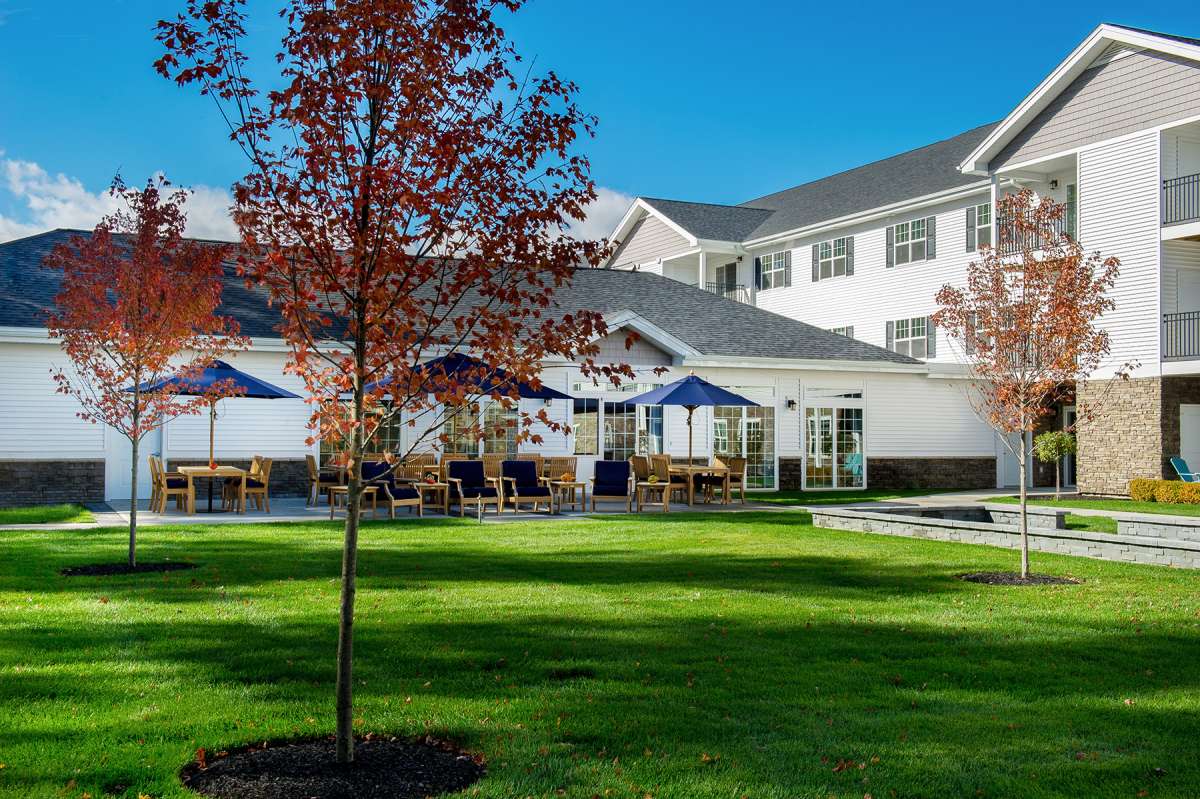 A well-maintained garden with patio seating in front of a residential building.
