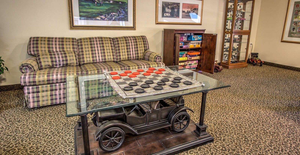 A cozy living room featuring a unique coffee table designed like a vintage car, with a checkers game set up on top.