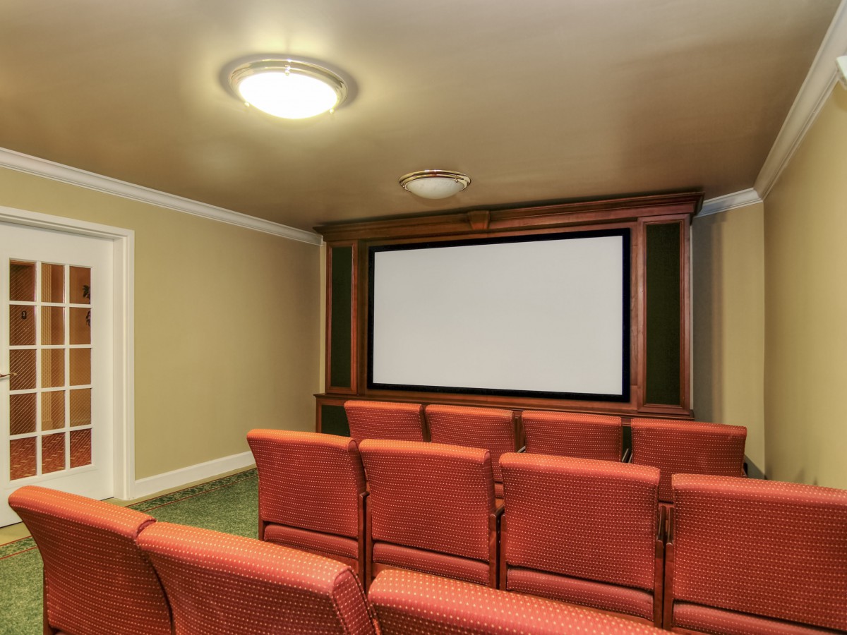 A cozy home theater with rows of comfortable seating and a large projection screen.