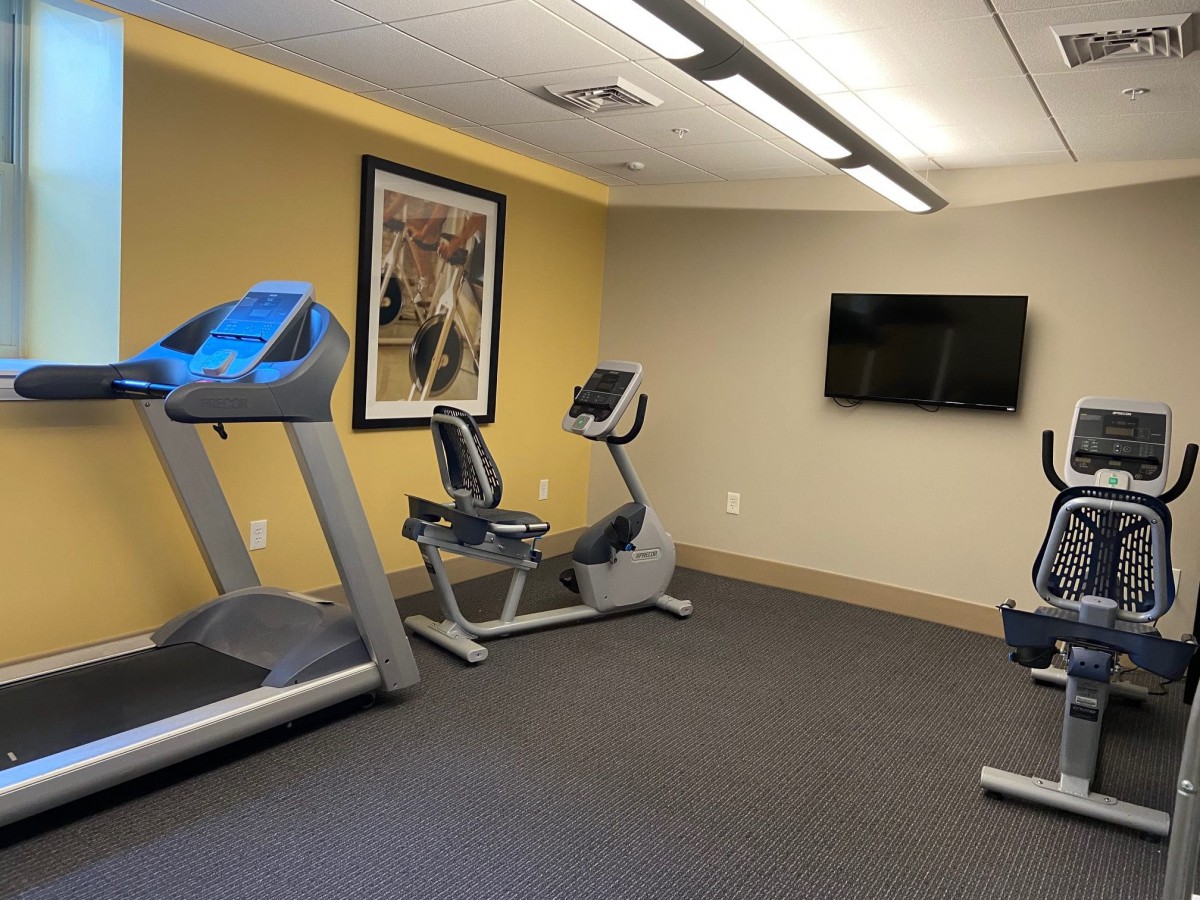 A small gym with a treadmill, exercise bikes, and a TV.