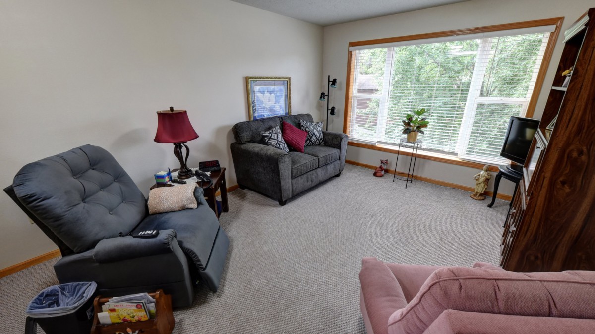 A cozy living room with a sofa, armchair, and large window overlooking greenery.