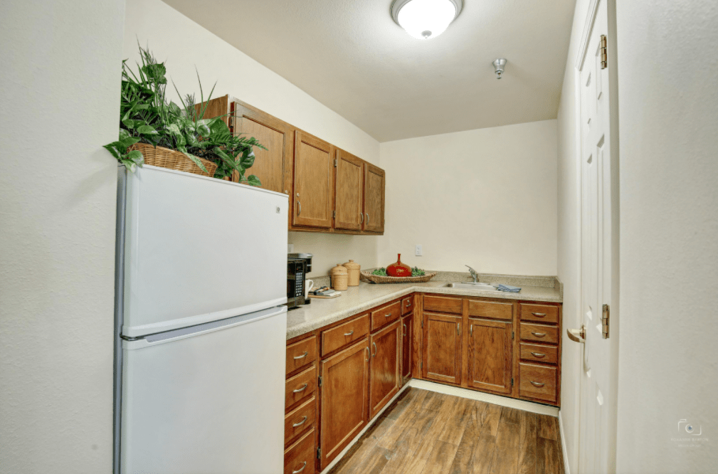 A cozy kitchen with wooden cabinets, a white refrigerator, and modern lighting.