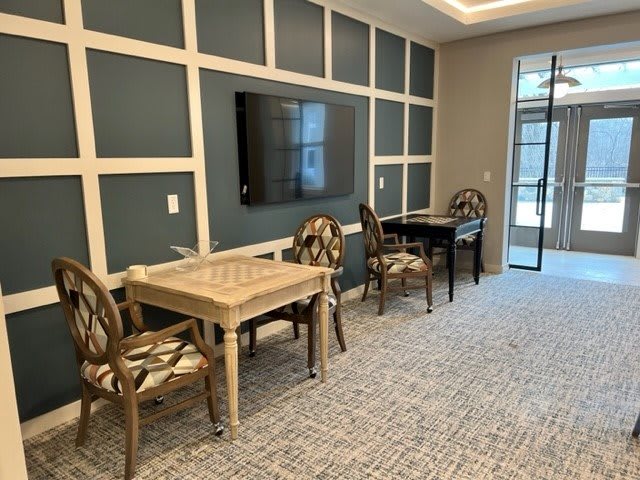 A modern conference room with tables, chairs, and a wall-mounted television.