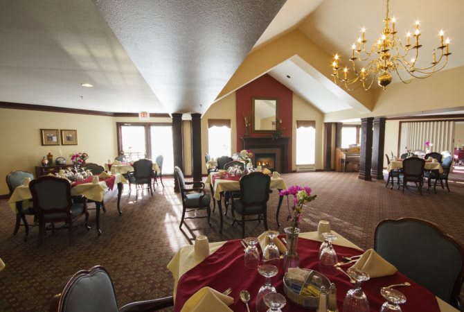 An elegant dining room with neatly arranged tables and a warm fireplace.