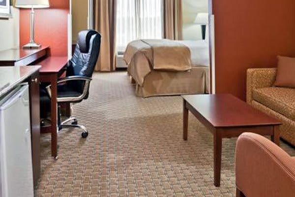 A spacious hotel room with a bed, desk, and chair.