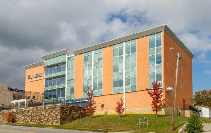 A modern building with a brick and glass facade under a partly cloudy sky.