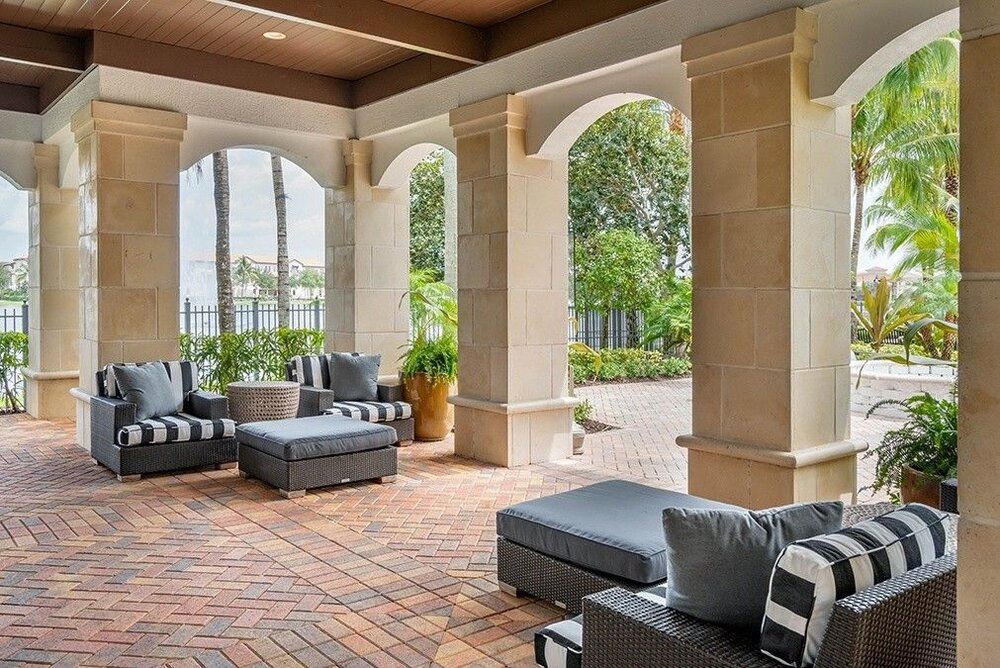 A stylish outdoor patio featuring comfortable seating and elegant columns, with a view of the garden.