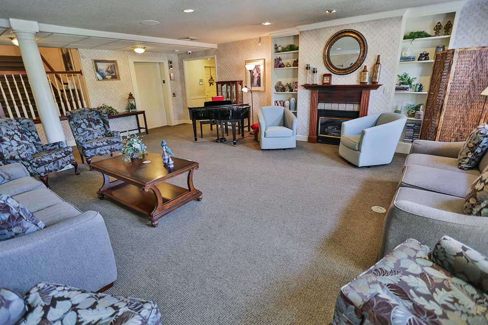 A cozy living room featuring a fireplace, comfortable seating and a piano.