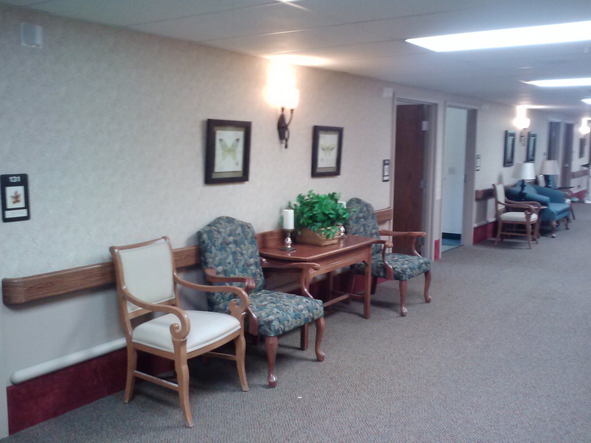 A hallway with seating and decor, featuring chairs and framed pictures.