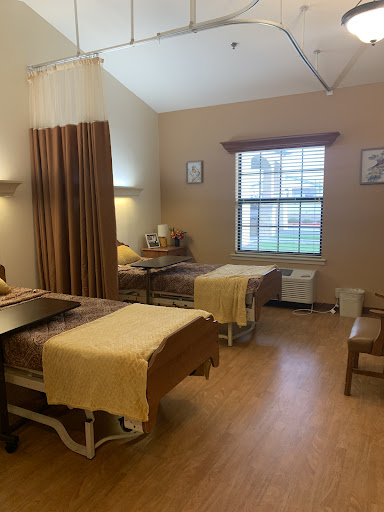 A well-lit hospital room featuring two beds, suitable for patient care.