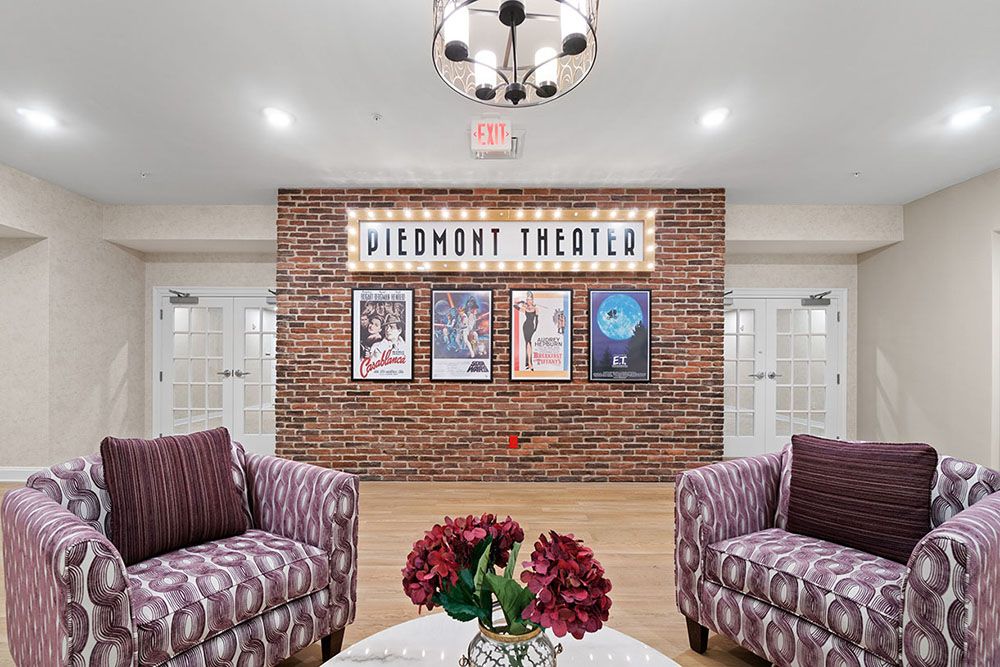 A cozy theater lobby with comfortable seating and movie posters on a brick wall.