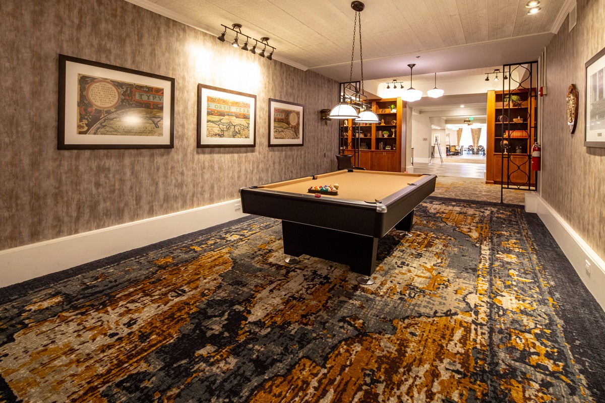 A cozy billiard room featuring a pool table, art on the walls, and warm lighting.