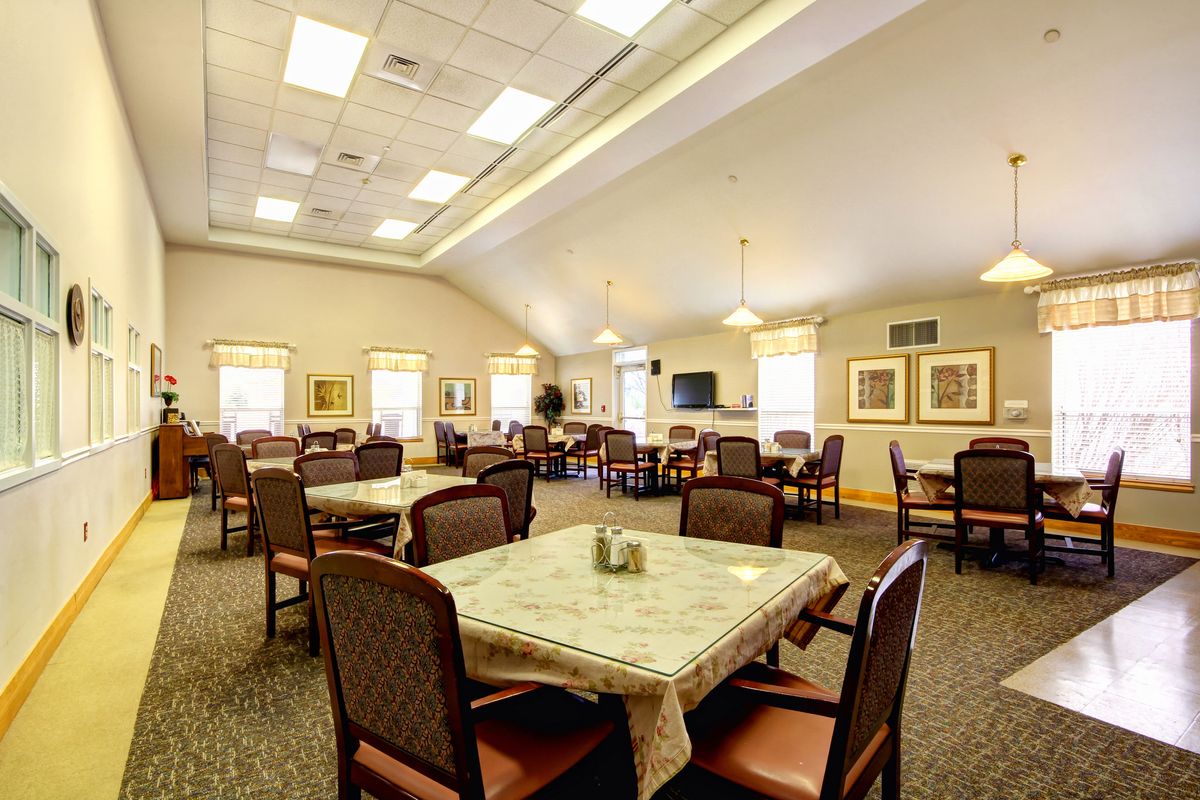 Spacious dining area with multiple tables and chairs, well-lit by ceiling lights and natural light from windows.