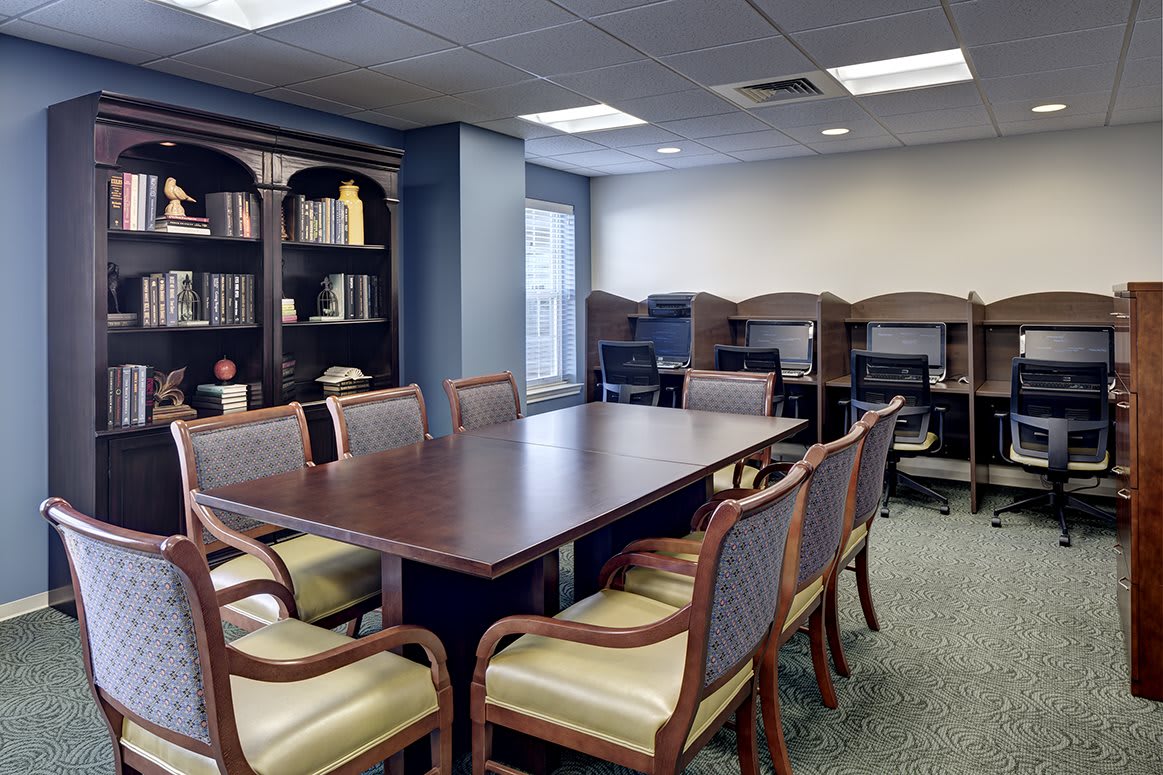 A well-furnished conference room with a large table, chairs, and surrounding bookshelves.