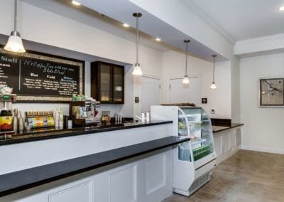 A modern cafe interior with a counter, menu board, and display case.