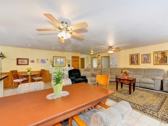 A cozy living and dining area with ceiling fans, comfortable sofas, a dining table, and tasteful decorations.