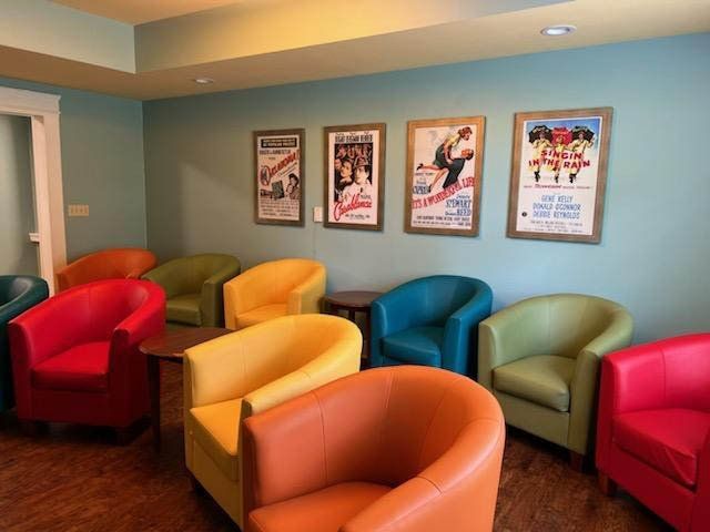 A colorful waiting room with a variety of chairs and framed posters on the wall.