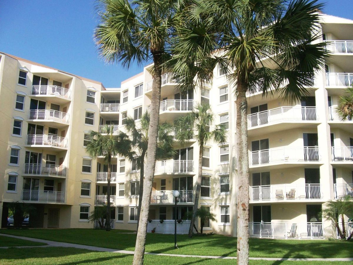 A sunny view of a residential apartment building with palm trees and balconies.