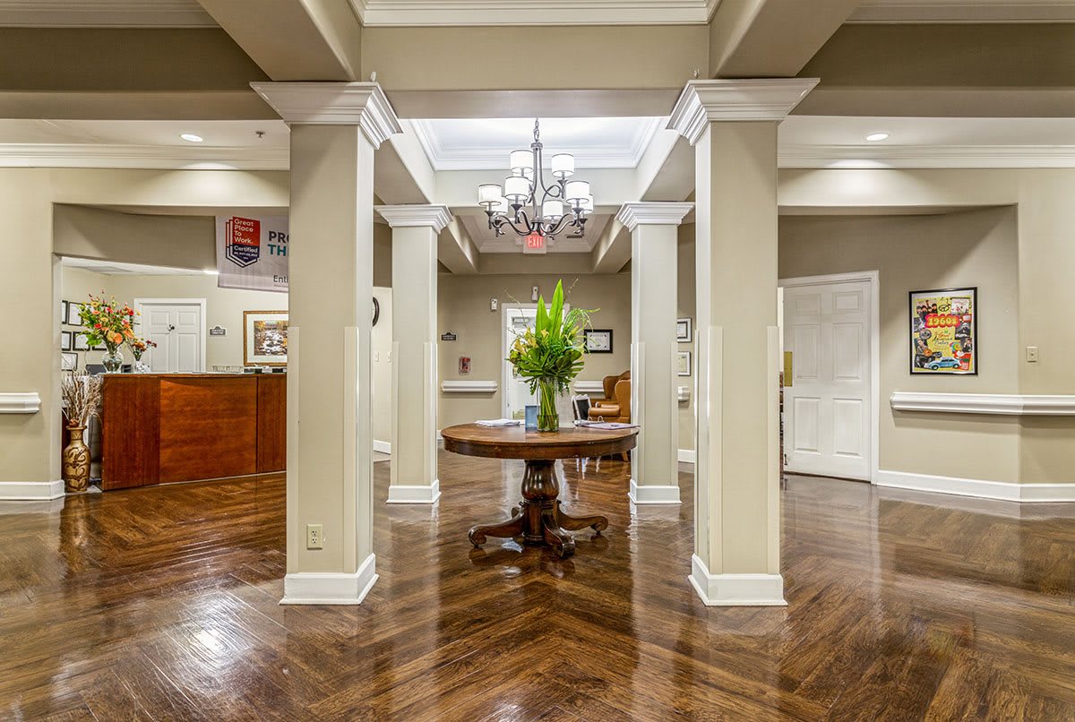 A well-lit lobby area with elegant columns and a central table featuring decorative plants.