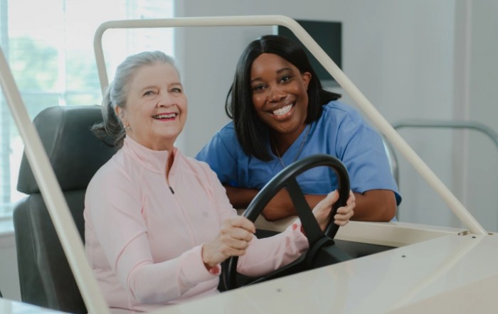 A healthcare professional assists an elderly patient in a rehabilitation setting, both smiling and engaged in the therapy session.