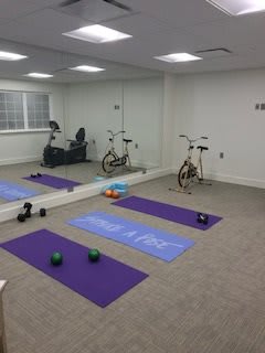 A home gym setup with yoga mats, dumbbells, and a stationary bike in front of mirrors.