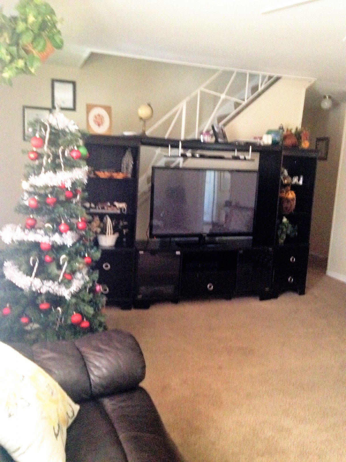 A cozy living room decorated for the holidays, featuring a Christmas tree and a large entertainment center.
