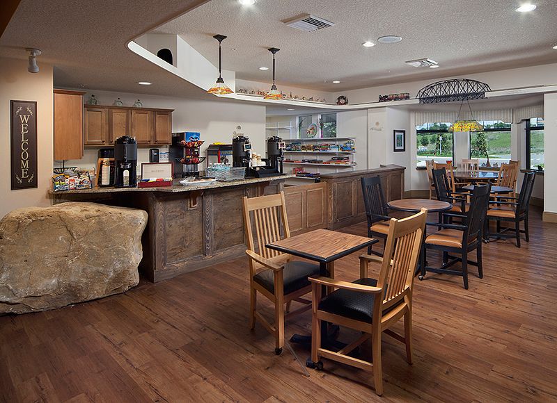 A cozy cafe interior with wooden tables and chairs, featuring a coffee counter and warm lighting.